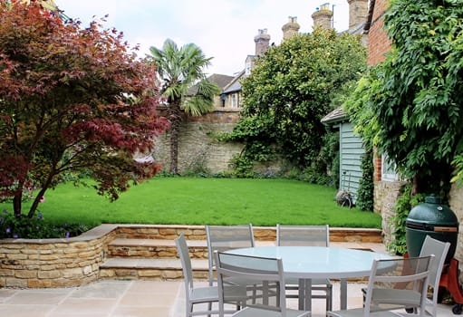 The finished walled garden with beautiful wide honey-coloured patio and retaining walls, with lush raised lawn